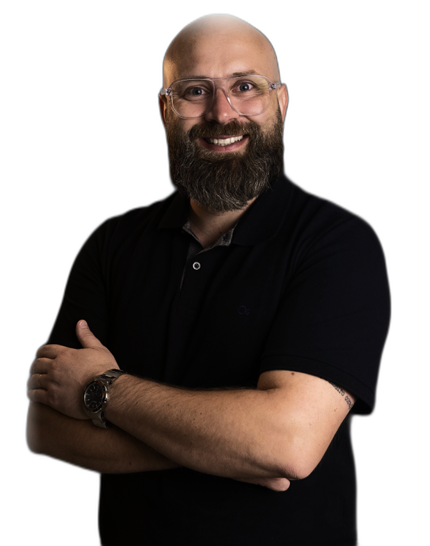 Cleomar Tenedini, consultor e mentor comercial, de camisa polo preta, sorrindo, de braços cruzados.